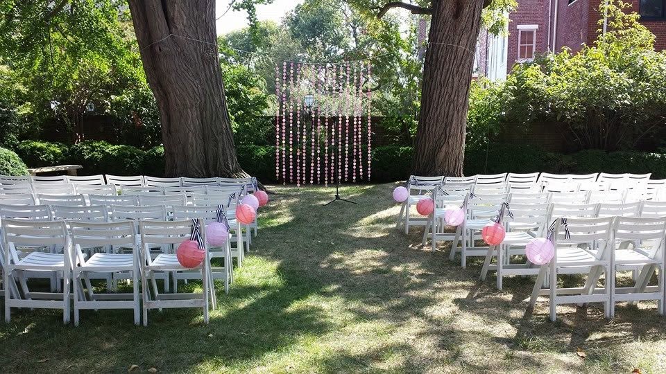 Rows of white chairs set for an outdoor garden wedding ceremony